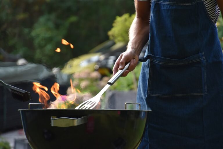 Familie genießt gemeinsames Grillen im Garten mit Kindern und sicheren Abstand